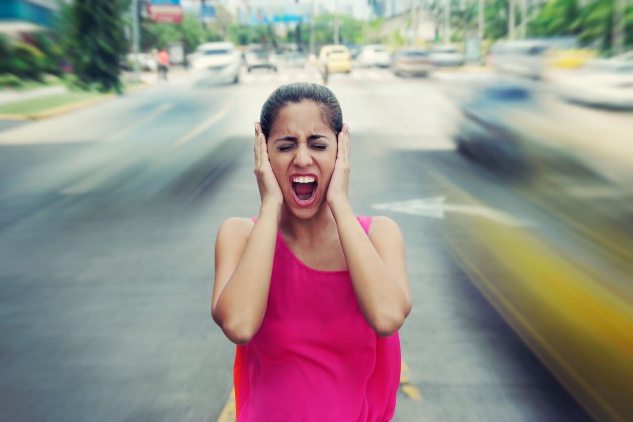 Mujer tapándose los oídos por la contaminación acústica
